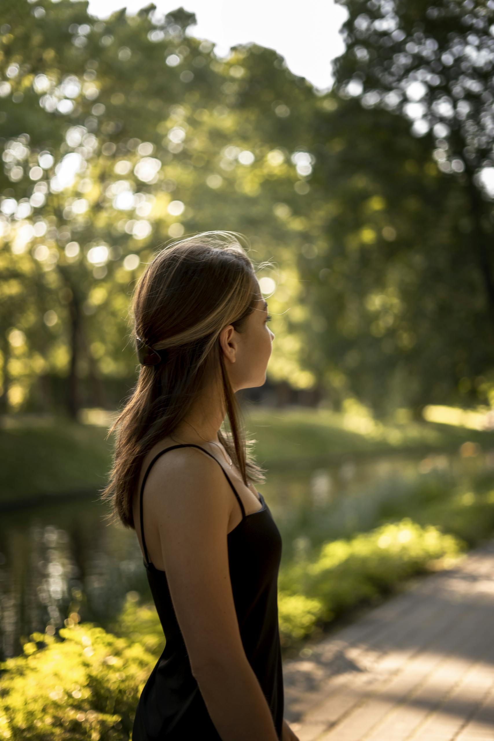 A young woman enjoying one of her self-date ideas by a tree-lined path during sunset.