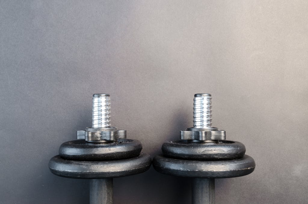 Close-up of two iron dumbbells on a gray background, one of the pieces of equipment for growing glutes