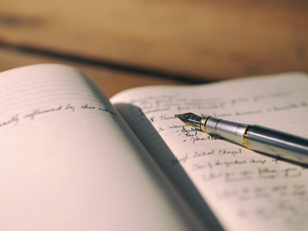 Pen resting on open DIY gratitude journal with wooden surface in the background