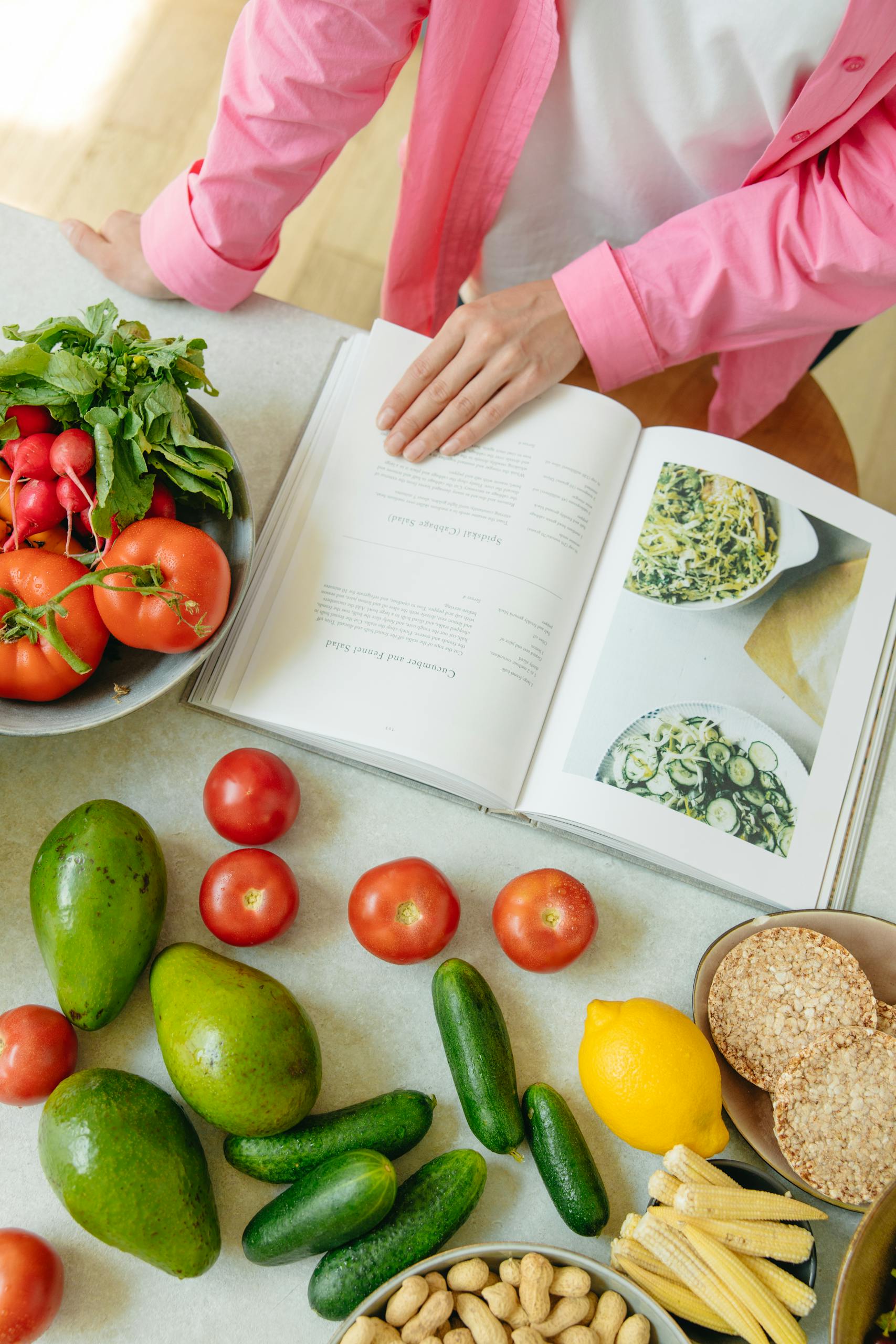 Overhead view of fresh vegetables and an open cookbook on a kitchen counter, learning for a 30-day challenge idea