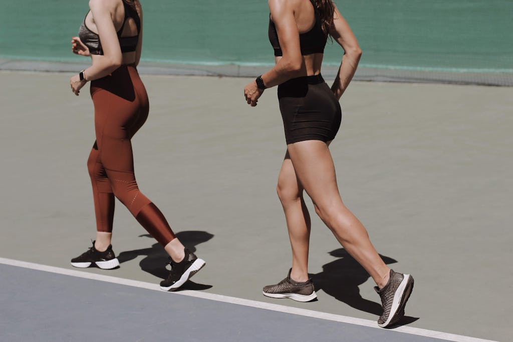 Two women walking on an outdoor track in sportswear, doing a 30-day challenge idea.