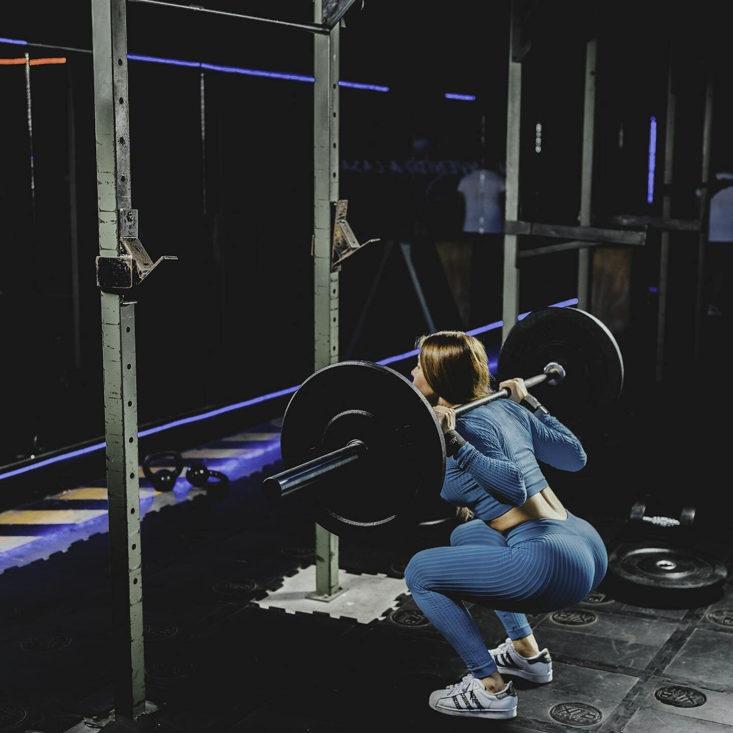 Woman squatting with a barbell in a gym, one of the best glute workout machines