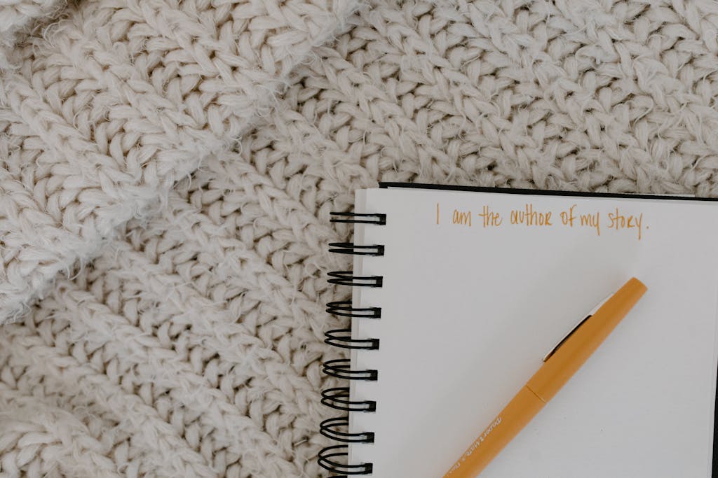 A notebook with motivational writing and pen on a knit blanket flatlay.