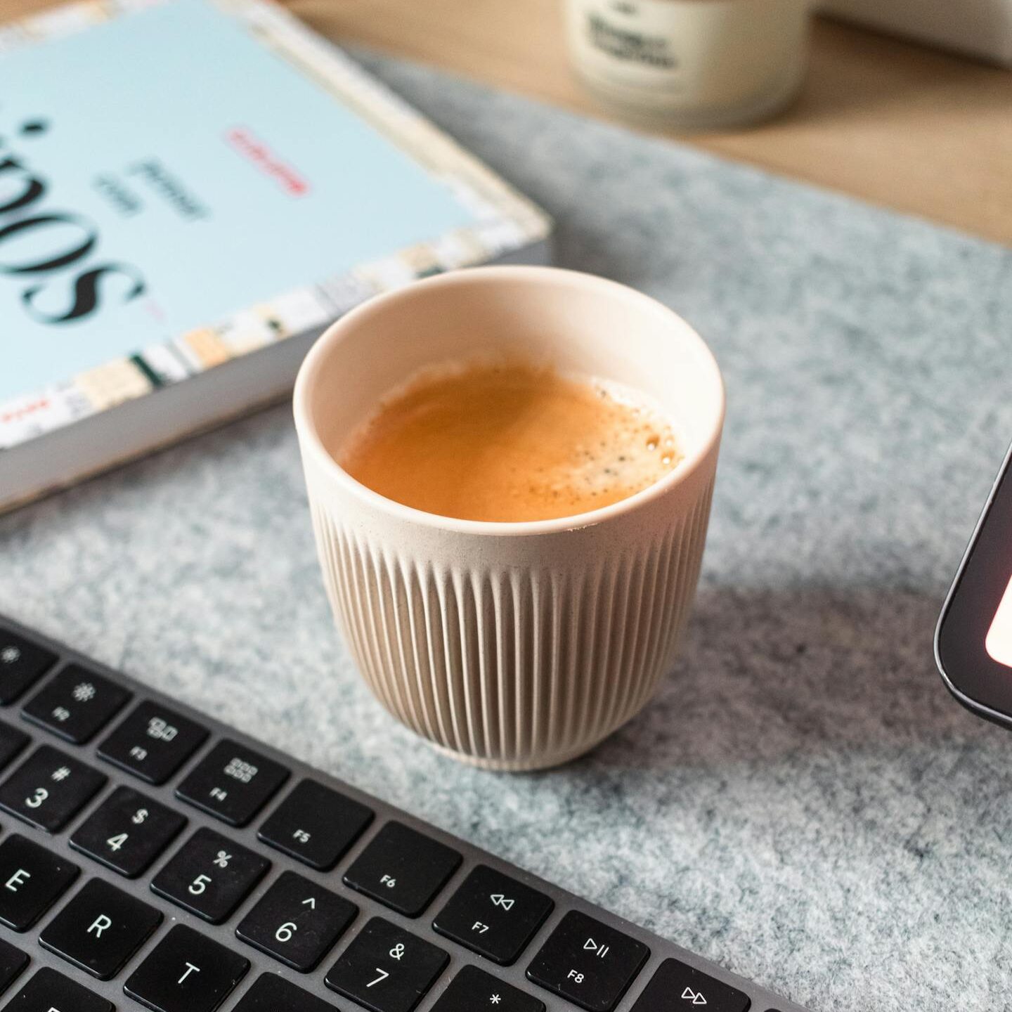 A stylish minimalist workspace featuring a coffee cup beside a keyboard.