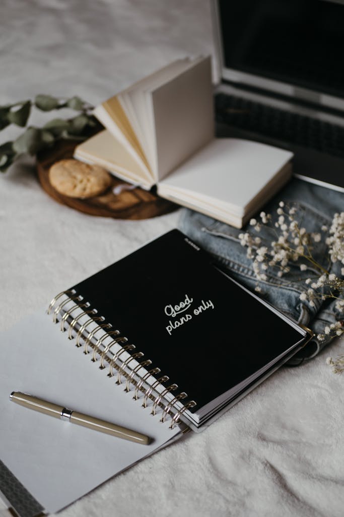 Inviting workspace setup featuring notebooks, a laptop, and cookies for a cozy sunday reset planning session.